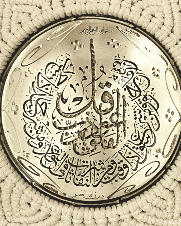 Close-up of circular gold metal plate with Quranic Arabic calligraphy, centerpiece of handmade macramé Islamic wall hanging