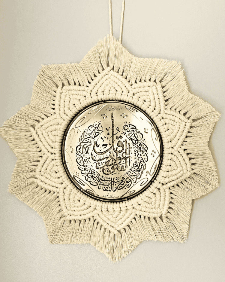 Handmade Islamic wall hanging featuring a gold metal plate with Arabic calligraphy, surrounded by intricate off-white macramé in a starburst pattern