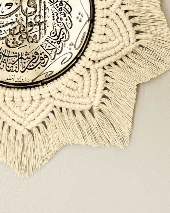 Detailed view of off-white macramé knots and fringe surrounding the gold Arabic calligraphy plate in a handmade wall decor piece