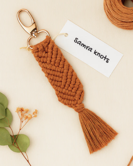 Rich terracotta macramé keychain on cream textured background, paired with Samra Knots branding.