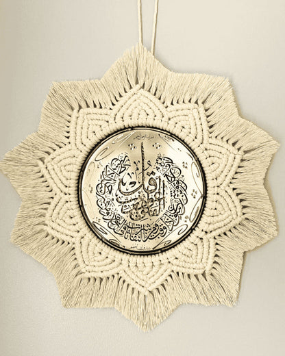 Handmade Islamic wall hanging featuring a gold metal plate with Arabic calligraphy, surrounded by intricate off-white macramé in a starburst pattern