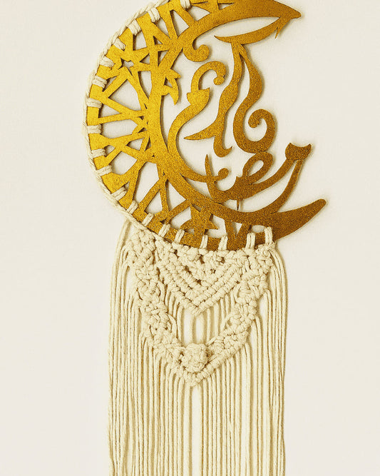 Handmade Islamic macramé wall hanging with gold crescent ayah plate and off-white cotton fringe, styled against a soft off-white background – Samra Knots.