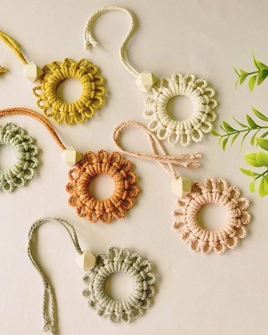Handmade macramé car diffuser keychains in soft pastel and earthy tones, featuring wood scent beads – styled flatlay on off-white background by Samra Knots.