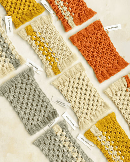 Flatlay of assorted handcrafted macramé mug rugs in earthy tones—grey, mustard yellow, off-white, and terracotta—designed by Samra Knots, arranged on a soft beige surface with brand tags.