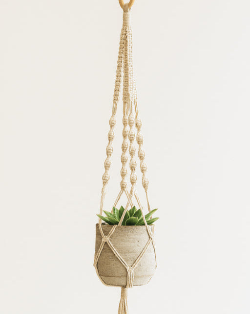 Off-white macramé plant hanger by Samra Knots, styled with a ceramic pot and succulent. Handmade boho decor using soft cotton cord.