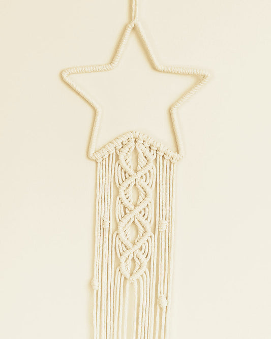 Handmade macramé star wall hanging in off-white cotton cord with elegant knotting and boho fringe design.